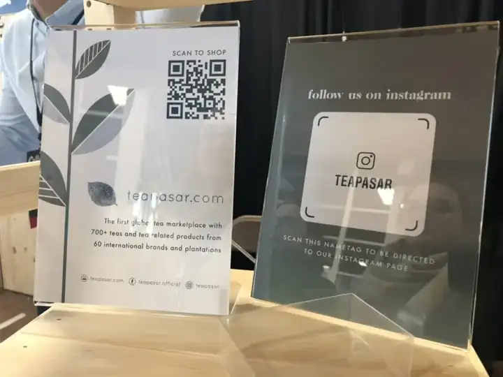 Teapasar signs at its festival booth: a QR code to shop teapasar.com and an Instagram nametag