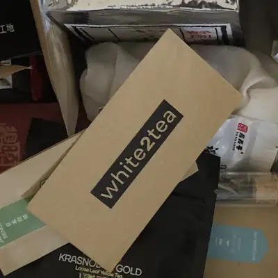 Kraft paper white2tea envelope lying on top of other tea packets in a box