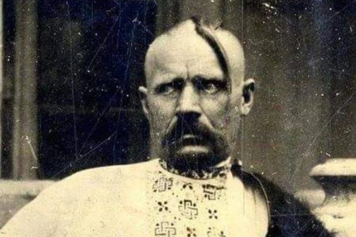 Old photograph of a Cossack with a shaved head and long forelock, in an embroidered shirt